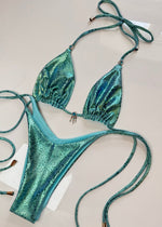 Shiny turquoise bikini set with textured pattern and beaded charm, laid flat on white surface