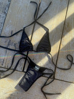 Black polka dot bikini set with tie straps on sandy wooden decking, handmade swimwear