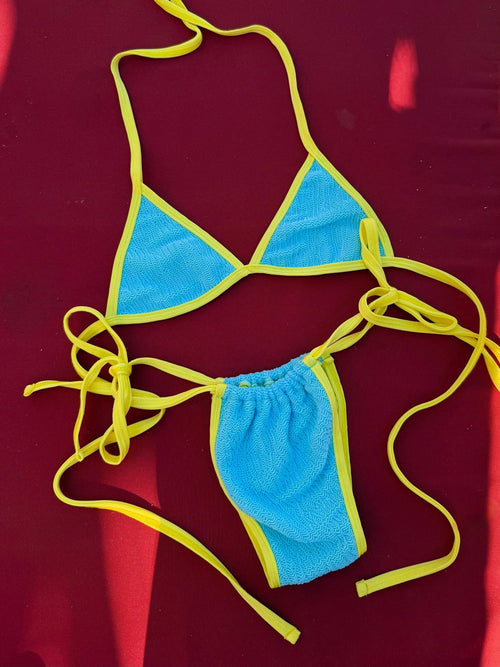 Blue and yellow reversible bikini set with tie straps on a red background