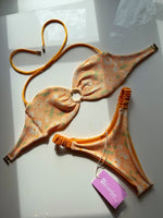 Handmade reversible floral bikini set with daisy print and yellow trim, displayed on white surface.