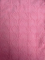 Pink textured fabric with embossed floral pattern, ideal for handmade swimwear, close-up view