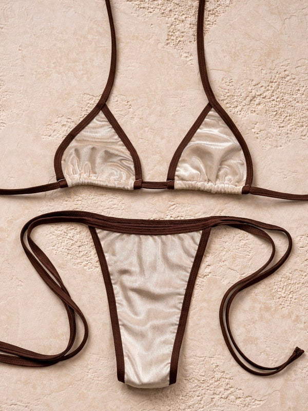 Handmade reversible bikini set with cream fabric and brown trim on neutral textured background