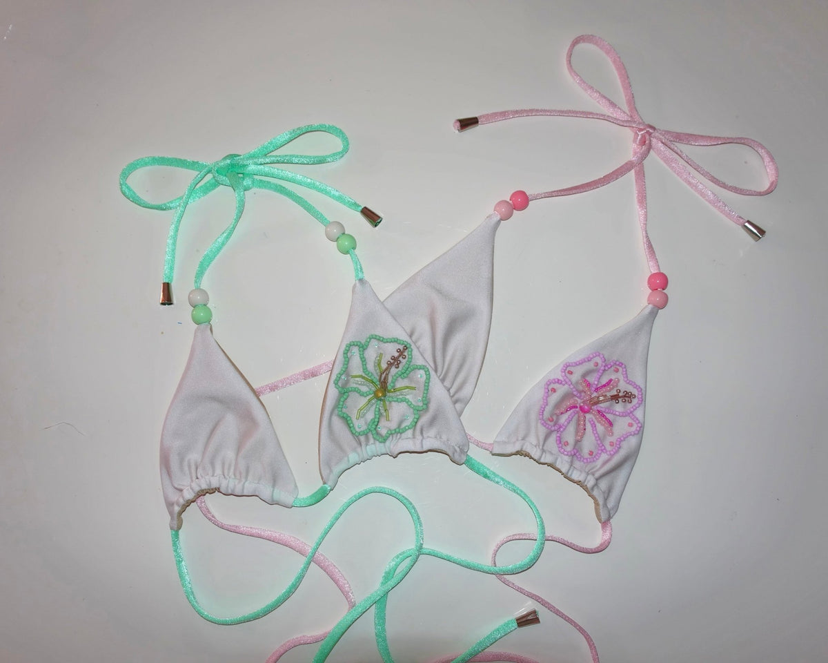 White bikini top with pastel beaded straps and embroidered floral designs on plain background