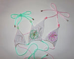 White bikini top with pastel beaded straps and embroidered floral designs on plain background