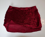 Red velvet mini skirt with textured fabric and wrap-style front, laid flat on white background