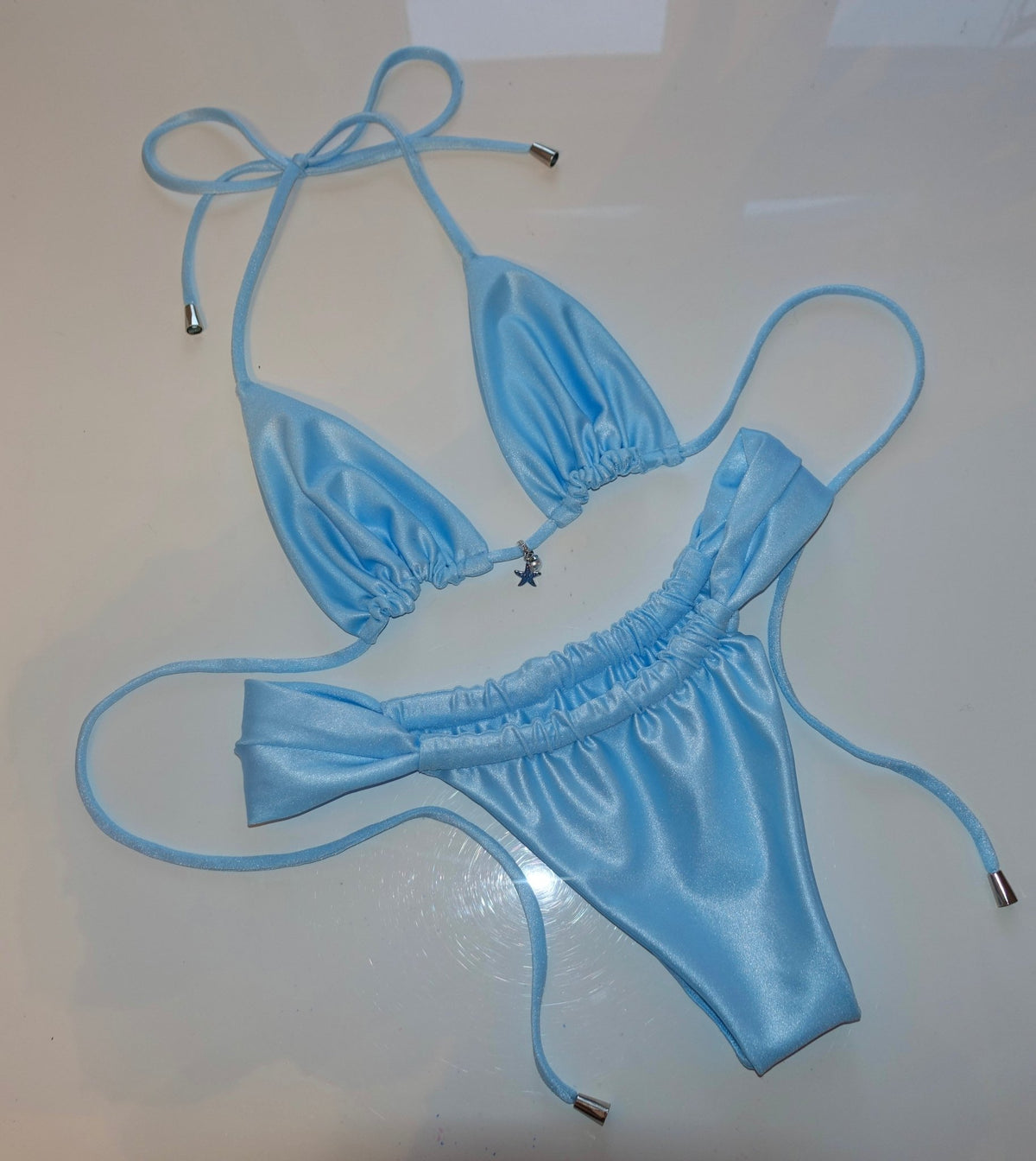 Light blue handmade reversible bikini with string ties and starfish charm on white background