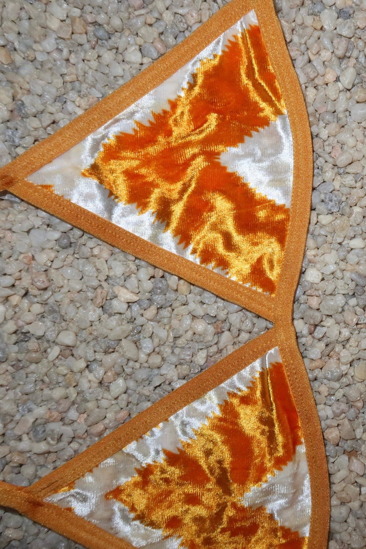 Handmade orange and white velvet triangle bikini top on pebble background