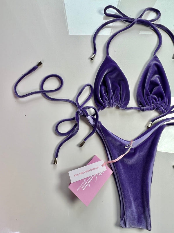 Purple velvet reversible bikini set with string ties and tags on a white background.