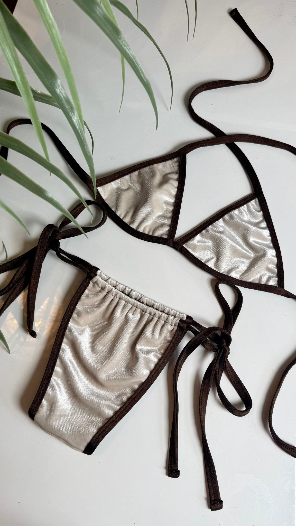 Handmade reversible bikini set with metallic silver fabric and brown trim, flat lay style