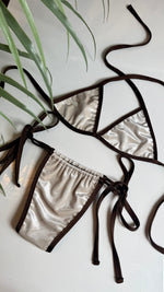 Handmade reversible bikini set with metallic silver fabric and brown trim, flat lay style