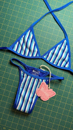 Blue and white striped bikini set with triangle top and butterfly tag on green grid background