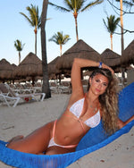 Woman in handmade reversible bikini lounging on hammock at tropical beach resort