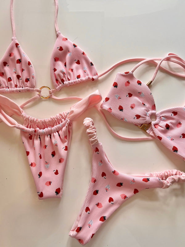 Pink handmade reversible bikinis with strawberry print on white background, sustainable swimwear