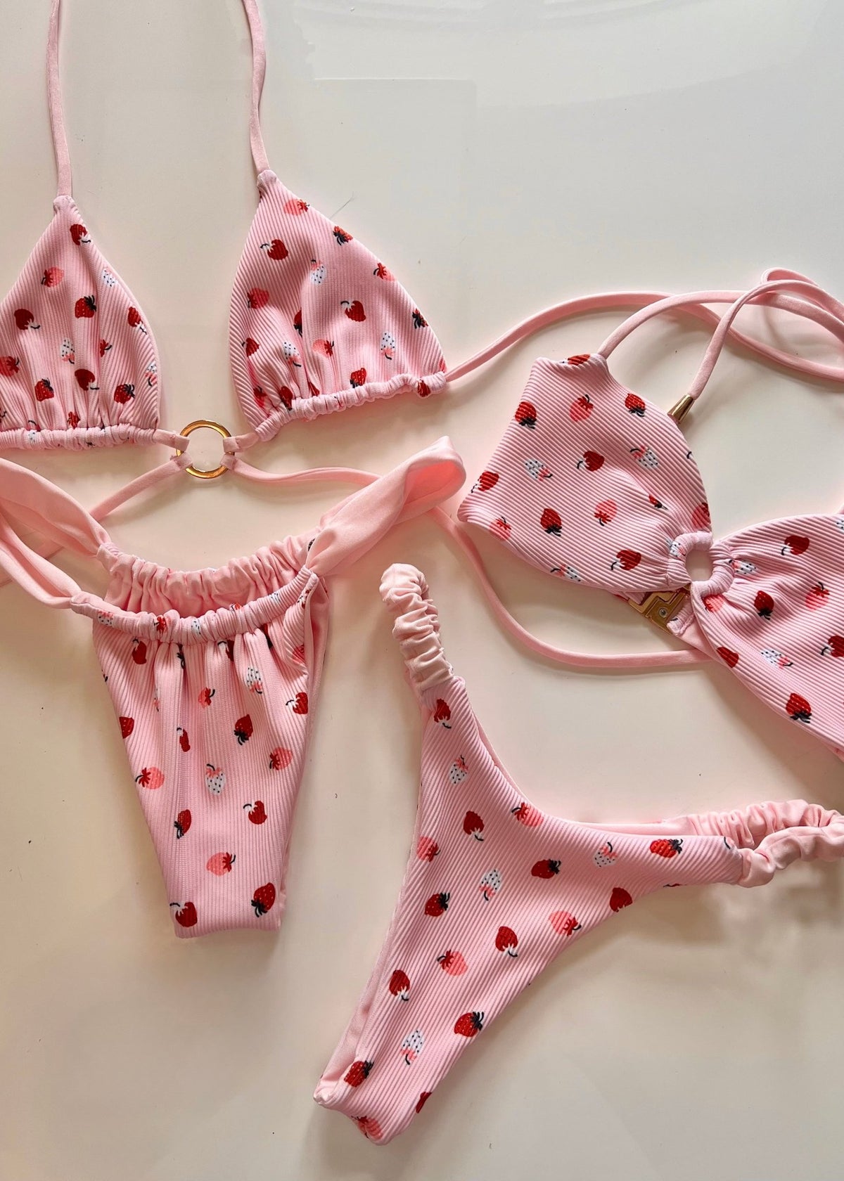 Pink handmade reversible bikinis with strawberry print on white background, sustainable swimwear