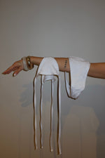 Hand holding a white reversible bikini top with textured fabric and tie straps