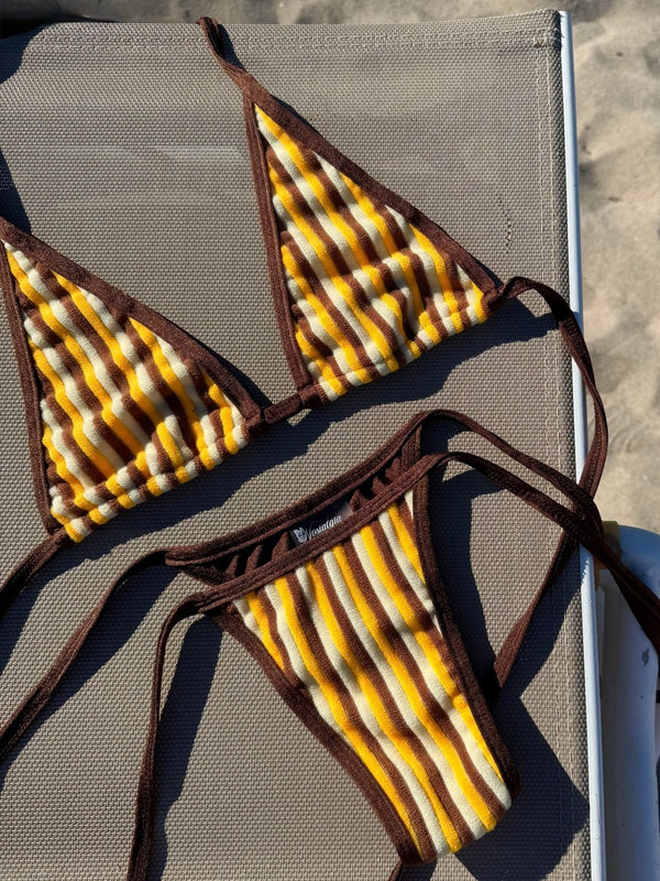 Yellow and brown striped handmade bikini set on a lounge chair at the beach