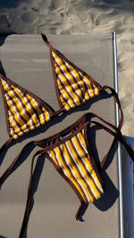 Yellow and brown striped handmade bikini set on a lounge chair at the beach
