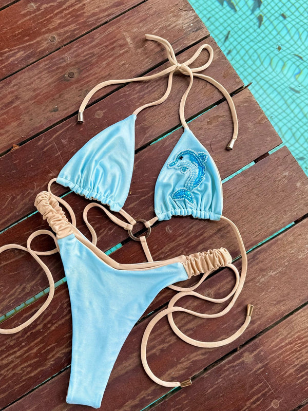 Light blue handmade bikini with beige straps and seahorse beaded detail by a pool