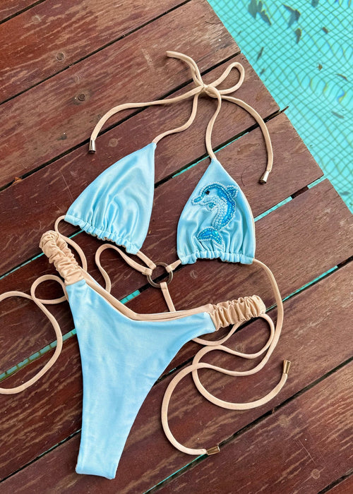 Light blue handmade bikini with beige straps and seahorse beaded detail by a pool
