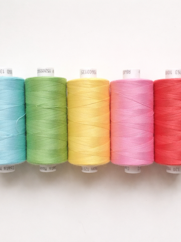 Colorful sewing thread spools in blue, green, yellow, pink, and red on white background