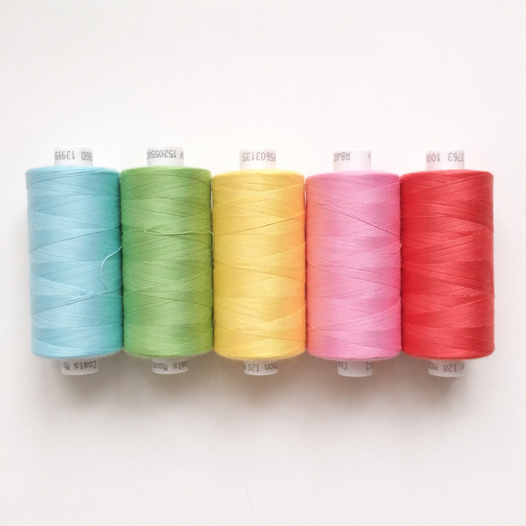 Colorful sewing thread spools in blue, green, yellow, pink, and red on white background