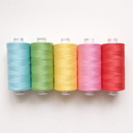 Colorful sewing thread spools in blue, green, yellow, pink, and red on white background