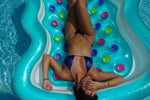 Woman in shiny blue bikini relaxing on colorful pool float in swimming pool