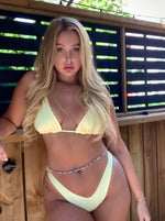 Woman wearing a handmade yellow bikini with beaded waist chain outdoors